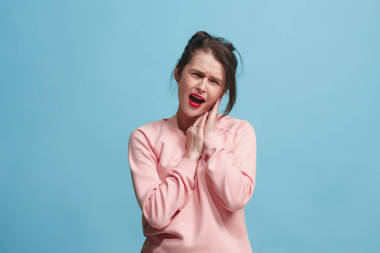 耳朵疼。在藍色演播室背景下頭疼或痛苦的哀傷的婦女