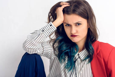 不满意的年轻女孩坐在白色的墙壁背景