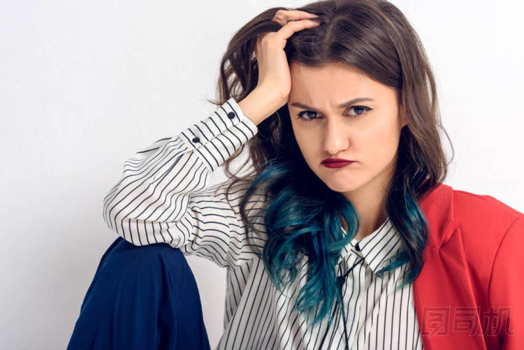 不滿意的年輕女孩坐在白色的墻壁背景