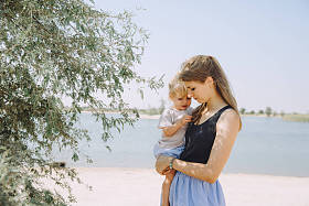 美丽的年轻母亲与她可爱的小女儿附近的树室外阳光明媚的一天