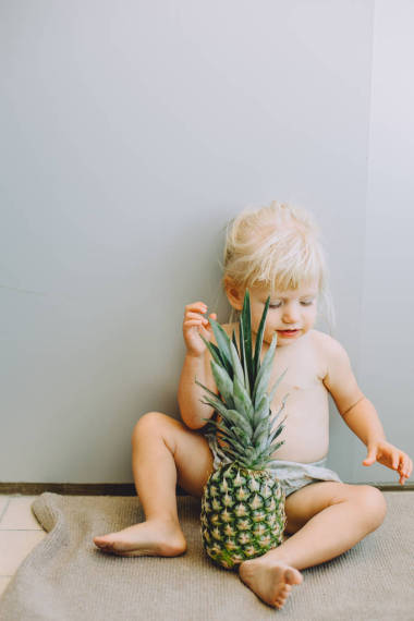 可愛的小女孩的肖像坐在地板上菠蘿