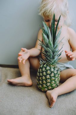 可爱的小女孩的肖像坐在地板上菠萝