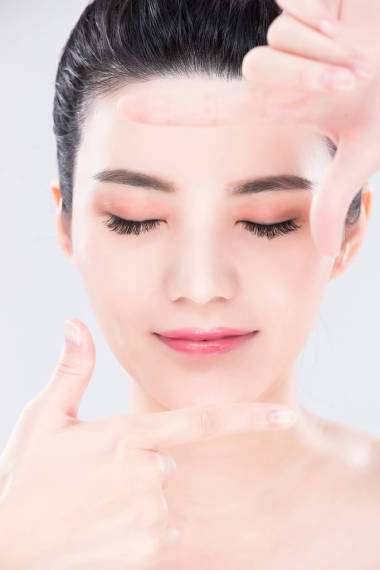 在灰色背景上做框架手勢的婦女