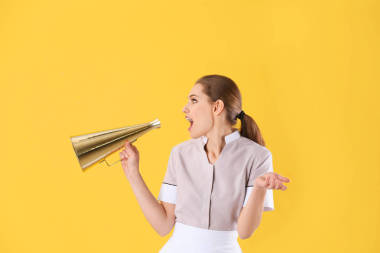 黄色背景扩音器的年轻女服务员