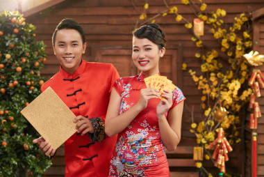 愛好亞洲情侶穿著中國傳統(tǒng)服飾, 展示彩色信封 