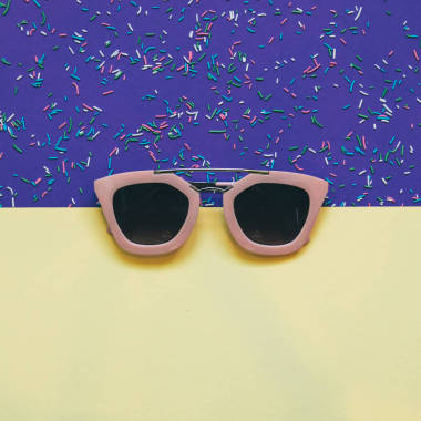 粉红色的太阳镜在黄色和紫外线魔术色的背景。简约主义与创意理念