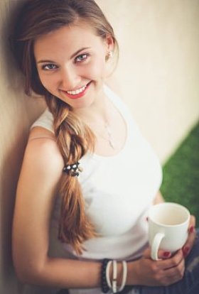 美丽的女人坐在地板上，捧着一杯。美丽的女人