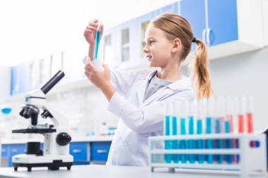 研究項(xiàng)目。有吸引力的好看漂亮的女孩升降小瓶充滿了試劑和在配置文件中擺姿勢