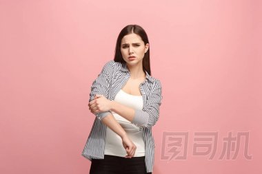 肘部疼痛。在粉紅色工作室背景下, 肘部疼痛或疼痛的悲傷婦女