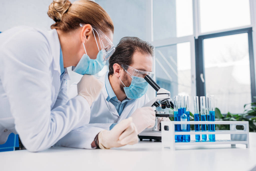 研究人员在白色大衣和医疗口罩一起使用试剂在实验室 研究人员在白色大衣和医疗口罩一起使用试剂在实验室