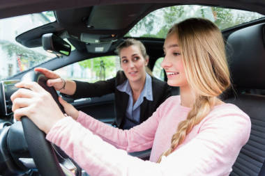 學生在汽車輪子駕駛課與她的老師