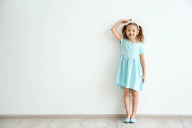 小女孩測(cè)量高度在輕的墻壁附近