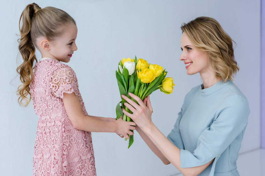 在妇女节给母亲一束郁金香的孩子女孩 在妇女节给母亲一束郁金香的孩子女孩