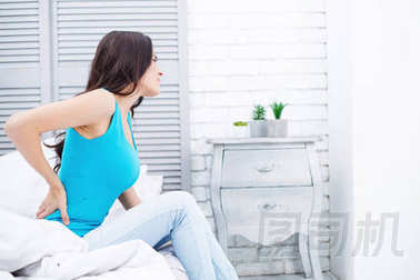 婦女的痛苦或月經(jīng)綜合癥。一個(gè)躺在家里床上的年輕女子抱著她的胃和卷發(fā)通過(guò)痙攣