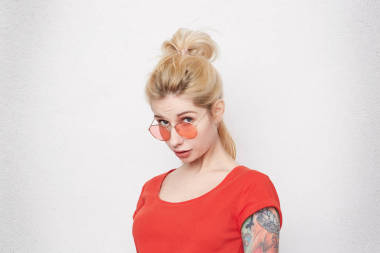 漂亮年輕的金發(fā)女孩的肖像害羞, 從腳下看。她昨天做錯了什么事。被隔絕的在白色混凝土墻