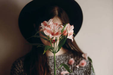 時尚的波西米亞女人手里拿著美麗的 alstroemeria 花。把注意力放在花上。生態(tài)概念。保存和保護