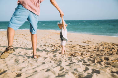 快樂的父親與可愛的小女兒漫步在沙灘上