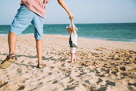 快乐的父亲与可爱的小女儿漫步在沙滩上