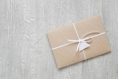 棕色工藝紙的信封用帶和標(biāo)簽在灰色木質(zhì)背景上用復(fù)制空間裝飾