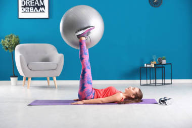 漂亮的年輕女子做健身運(yùn)動與球在家