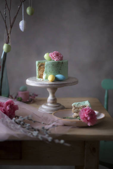 自制复活节蛋糕片在装饰性假日餐桌上的特写与心疼的鸡蛋和春天的花朵