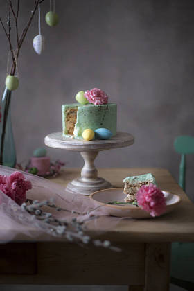 自制复活节蛋糕片在装饰性假日餐桌上的特写与心疼的鸡蛋和春天的花朵