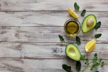 鱷梨一半的蔬菜和油在木質(zhì)的背景。頂部視圖