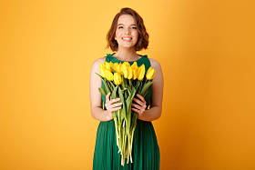 橙色的黄色郁金香花束捧着微笑的女人的肖像