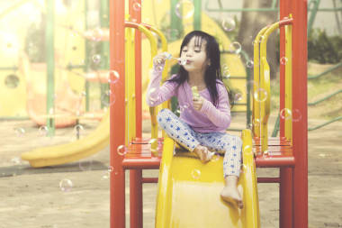 小女孩在操場上玩肥皂泡。夏季和春季概念