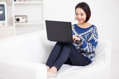 使用便攜式計(jì)算機(jī)的年輕亞裔女子