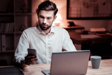 感興趣的英俊的工人選址和使用他的手機.