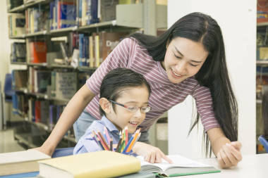 女教師和兒童學生在書架背景下學習書籍
