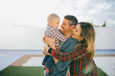 快乐家庭的妈妈和爸爸抱着一个婴儿在家里玩