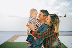 快乐家庭的妈妈和爸爸抱着一个婴儿在家里玩