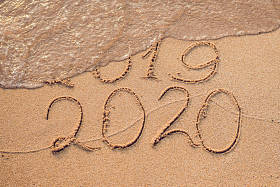 新年2020是未来概念-题字2019和2020沙滩沙子, 波浪几乎覆盖数字2019