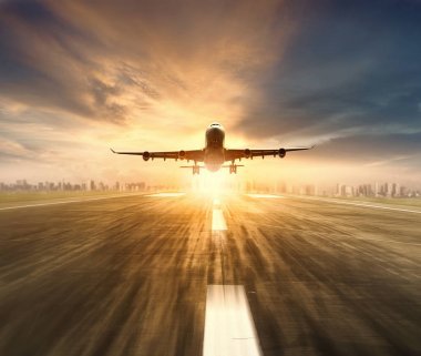 飛機(jī)飛越機(jī)場(chǎng)跑道與城市景觀和日落