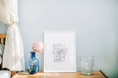 相框与书法报价那里有光明有希望, 普罗蒂亚花在花瓶前面的粉彩蓝墙。模拟帧