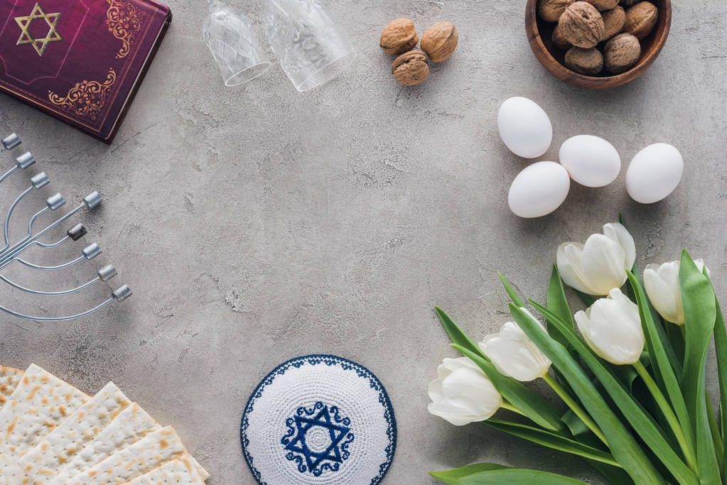 传统书中的希伯来文、kippah 和烛台在混凝土桌上的顶部视图