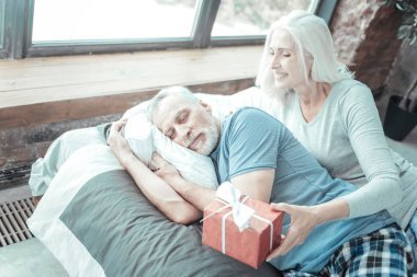 可愛的資深婦女接近她的丈夫和藏品禮物.