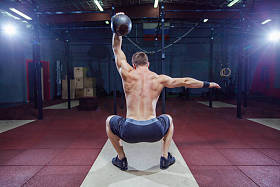 交叉配合训练。健身人通过提升壶进行举重训练。年轻的运动员做壶摆动。健美运动员提升壶。健身房的交叉健身教练。交叉配合在