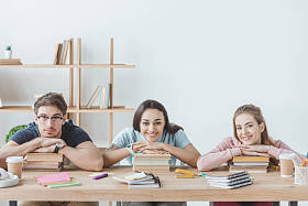 坐在桌边看书和抄写本旁的年轻多文化学生