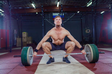 肌肉健美男子準備硬拉起杠鈴在他的頭在現(xiàn)代化的健身中心。功能性訓(xùn)練。抓舉運動