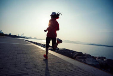 運動的年輕健身婦女運行在日出海濱