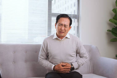 坐在沙發(fā)上的亞洲老人胃痛 照片
