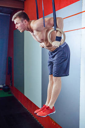 肌肉锻炼年轻人做激烈的交叉健身运动在健身房体操戒指