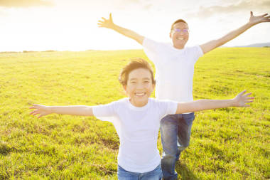 快樂的家庭父親和孩子在草地上奔跑