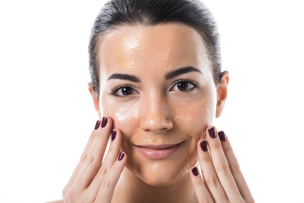 美丽的女孩触摸与蜂蜜面具的脸, 看着相机在白色隔离 美丽的女孩触摸与蜂蜜面具的脸, 看着相机在白色隔离