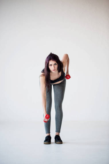 严肃的 sportwoman 在工作室里用哑铃做手工练习。全长前视图