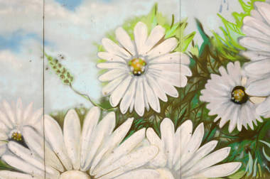 墻壁的背景紋理與涂鴉畫。藍(lán)色多云的天空和白色的花朵