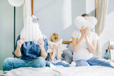 幸福的家庭觀念。爸爸, 懷孕的媽媽和兒童女孩在床上